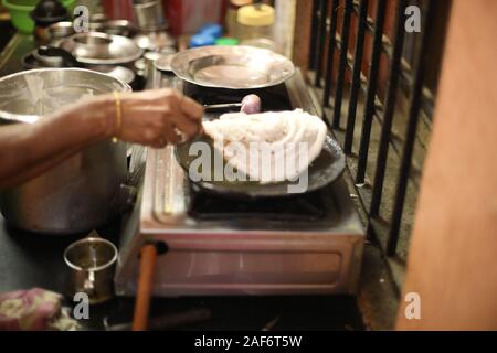 Dosa il cibo indiano. donne mano la cottura o la realizzazione di dosa in cucina, India. Sud indiano vegetariano, Foto Stock