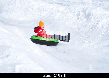 Bambino ragazza su tubi di neve in discesa al giorno d'inverno. Foto Stock