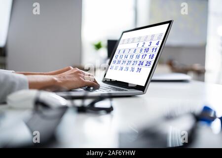 Giovane imprenditrice guardando il Calendario sul computer portatile alla reception Foto Stock