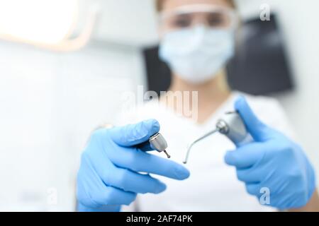 Primo piano delle mani della donna azienda dentista strumenti nelle sue mani. Messa a fuoco selettiva. Foto Stock