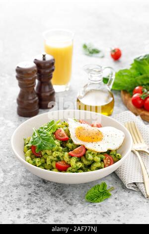 Pasta cavatappi con Pesto di spinaci, pomodori e uova fritte nel recipiente per il pranzo Foto Stock