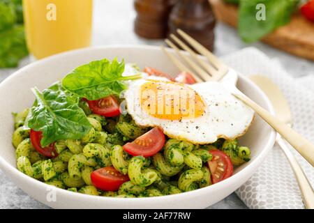 Pasta cavatappi con Pesto di spinaci, pomodori e uova fritte nel recipiente per il pranzo Foto Stock