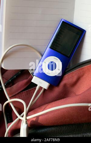 Milano, Italia - 4 giugno 2019. Blu Apple iPod Nano 8GB Lettore musicale con cavo caricabatterie attaccato su notebook e zainetto sfondo Foto Stock