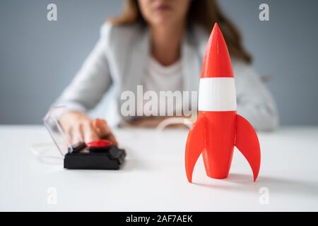 Imprenditrice la mano a razzo di lancio premendo il pulsante rosso Foto Stock