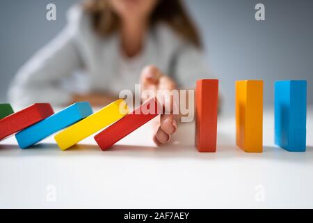 Elevato angolo di visione di un imprenditore colorato di arresto di domino di cadere sulla scrivania Foto Stock