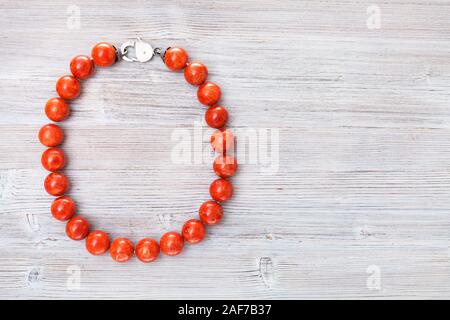 Vista superiore del corallo rosso collana grigia su tavola di legno con copyspace Foto Stock