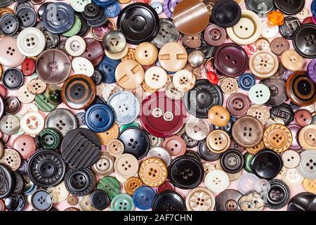 Vista superiore della pila di molti diversi pulsanti vicino sul rosa Foto Stock