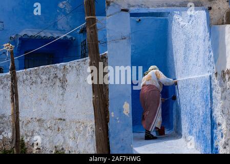 Donna pittura pareti iin Chefchaouen Foto Stock