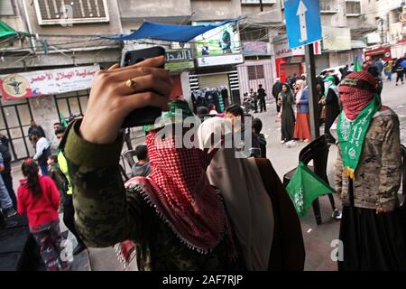 Khan Younis, Gaza. Xiii Dec, 2019. Una mascherata Ragazza palestinese scattare foto del mio predecessore al telefono durante un rally segnando il trentaduesimo anniversario della fondazione del movimento islamico di Hamas a Khan Yunis nel sud della striscia di Gaza il Venerdì, il 13 dicembre 2019. Foto di Ismael Mohamad/UPI. Credito: UPI/Alamy Live News Foto Stock
