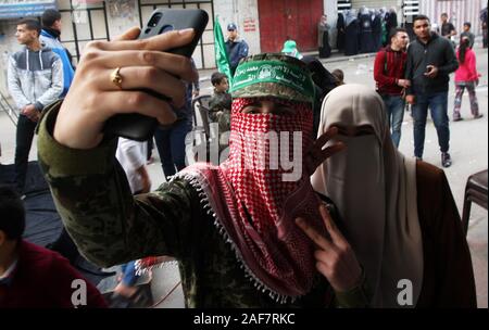 Khan Younis, Gaza. Xiii Dec, 2019. Una mascherata Ragazza palestinese scattare foto del mio predecessore al telefono durante un rally segnando il trentaduesimo anniversario della fondazione del movimento islamico di Hamas a Khan Yunis nel sud della striscia di Gaza il Venerdì, il 13 dicembre 2019. Foto di Ismael Mohamad/UPI. Credito: UPI/Alamy Live News Foto Stock