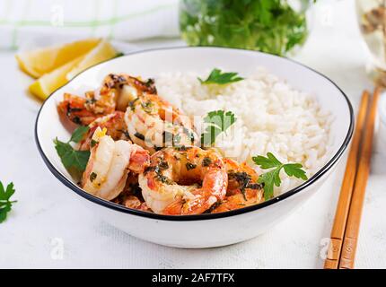 Grigliata di gamberi e riso bollito. Re code di gamberi in arancione-salsa di aglio con prezzemolo. Foto Stock