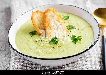 In casa la crema di broccoli zuppa con crostini nella ciotola bianco su sfondo grigio. Una sana alimentazione vegetariana. Menu vegano. Foto Stock
