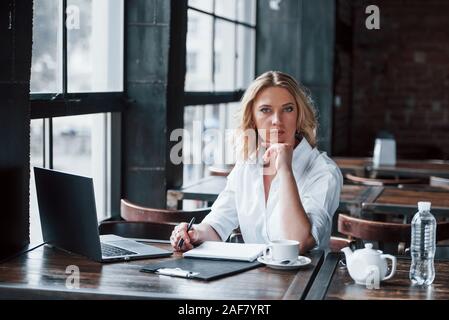 Piacere di conoscerti. Imprenditrice con ricci capelli biondi in ambienti interni in cafe di giorno Foto Stock