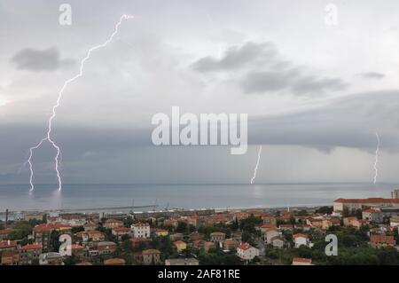 I temporali su mare Adriatico vicino a Rijeka. Fulmini, tempesta e la pioggia sopra la città di notte Foto Stock