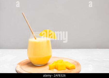 Yogurt a base di bevanda indiana Mango Lassi su grigio sfondo neutro con spazio di copia Foto Stock