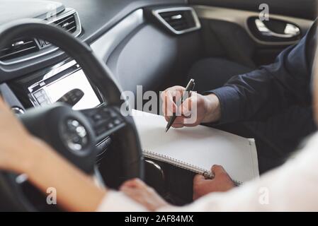 La scrittura di informazioni importanti. Assistente manager fornendo consigli e aiuto al cliente nel Salon Automobile Foto Stock