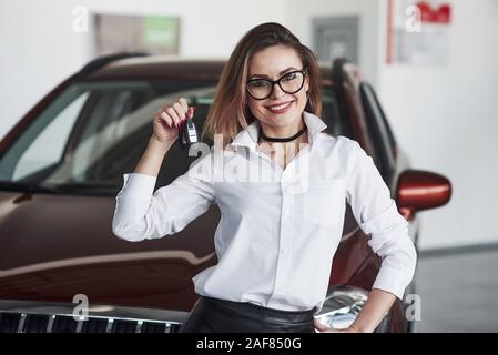 Gentile responsabile femmina si erge contro auto rossa nel Salon Automobile Foto Stock