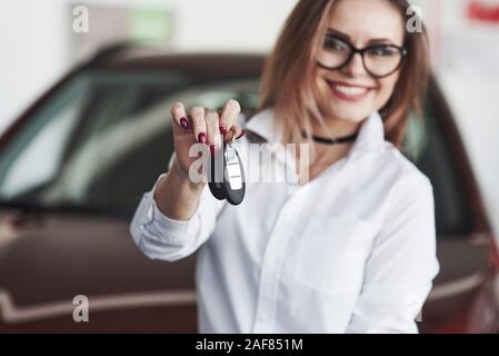 Il tuo acquisto è fatto. Gentile responsabile femmina si erge contro auto rossa nel Salon Automobile Foto Stock