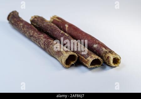 Tre bastoni di carni bovine essiccate esofago. Close-up di chicche secchi per cani su uno sfondo bianco. Messa a fuoco selettiva. Non isolare. Foto Stock