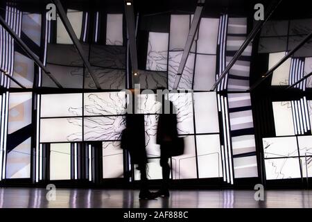 22 novembre 2019 Montreal, Quebec, Canada: Due Passersby che si incrociano davanti a una parete astratta dello schermo in background, Motion Blur, Place des Arts Foto Stock