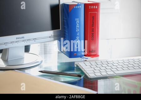 Parigi, Francia - 13 Marzo 2016: codice francese del lavoro libro è raffigurato con computer su una scrivania in studio su una giornata invernale Foto Stock