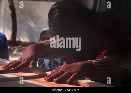 Dacca in Bangladesh. Xiii Dec, 2019. Una donna si siede accanto a suo marito della bara all'obitorio di Dhaka Medical College Hospital di Dhaka.almeno 13 persone sono state uccise e quasi venti persone sono state gravemente ferite quando un incendio spazzato attraverso un sistema illegale di fabbrica di plastica al di fuori della capitale del Bangladesh Dhaka. Credito: SOPA Immagini limitata/Alamy Live News Foto Stock