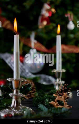 Flaming candele in argento antico portacandele con albero di Natale decorato a sfondo. Foto Stock