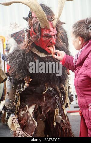 Monaco di Baviera, Germania - Dicembre 8, 2019 Una donna tocca la lingua di legno della maschera di un attore presso il tradizionale Krampus eseguito nel centro di Monaco di Baviera, demon Foto Stock