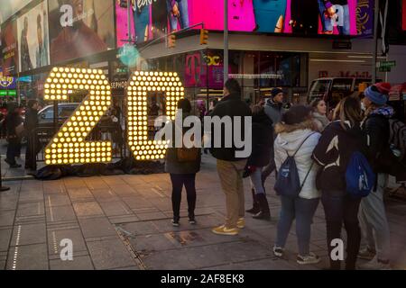 New York, NY/USA-dicembre 12, 2019 i visitatori a Times Square a New York pongono di fronte due sette piedi di altezza i numeri "2" e "0" in Times Square a New York il Mercoledì, Dicembre 12, 2019 . Il "20" sarà parte del display LED sulla cima di una Times Square che si illumina fino alla mezzanotte del 1 gennaio la compitazione dei "2020" inaugurando il nuovo anno. Sette piedi numeri alti uso efficiente dal punto di vista energetico lampadine LED che durerà un anno intero senza mai dover essere modificato. (© Richard B. Levine) Foto Stock