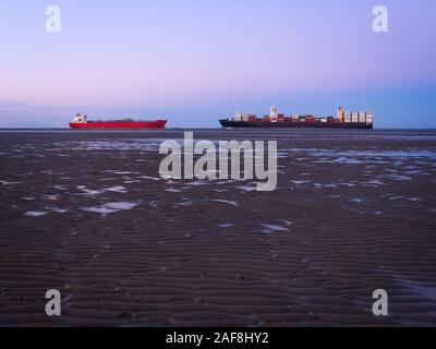 Due navi passando la bocca del fiume Elb in diverse direzioni vicino Otterndorf a bassa marea del mare di Wadden davanti a una bella sk pastello Foto Stock