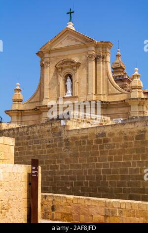 La facciata della Cattedrale dell'Assunzione alle spalle massicce mura della cittadella di Victoria a Gozo, Malta Foto Stock
