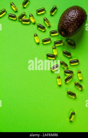 Fila avocado su backgroundand verde un sacco di capsule con olio di avocado o olio di pesce, cucina creativa concept Foto Stock