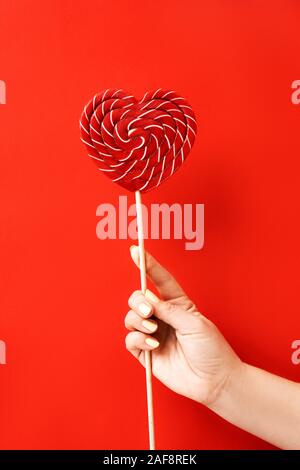 Femmina lato tenendo un grande blu e bianca a strisce lecca-lecca Foto Stock