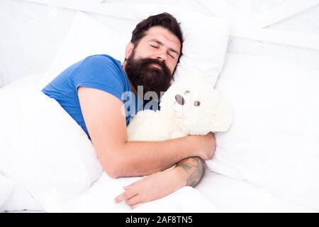 Tanga pigro relax nella camera da letto. Buona notte e dolci sogni. uomo barbuto orsacchiotto a letto. Il giocattolo di peluche concetto. buon compleanno presente. è il momento di andare a dormire. trascorrere il weekend a letto. Confortevole a casa. Foto Stock