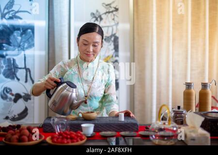 Una donna in abito tradizionale che fa il tè con il metodo tradizionale cinese utilizzando un tradizionale Yixing ware argilla viola teapot, Yixing, Cina Foto Stock