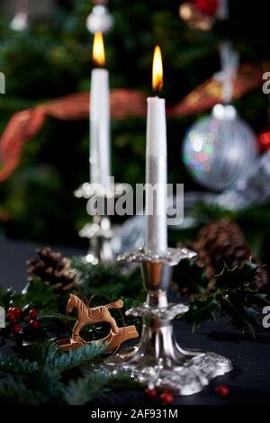 Flaming candele in argento antico portacandele con albero di Natale decorato a sfondo. Foto Stock