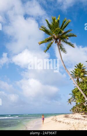 Una donna che cammina lungo una spiaggia tropicale idilliaco Foto Stock