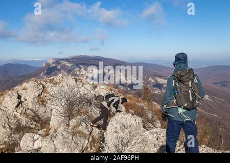 Due gli escursionisti di montagna cercando di passare oltre stretto, pericoloso, scivolose, Rocky Mountain ridge in una giornata di vento con phantom blue sky Foto Stock