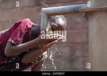 Splendida Africana Schoolgirl Bere Acqua Sana Dal Rubinetto - Giornata Mondiale Dell'Acqua Foto Stock