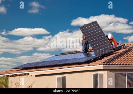 I lavoratori di installare pannelli solari sul tetto di casa. Foto Stock