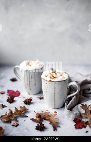 Zucca Latte speziato con panna montata Topping e spolverata di cannella circondata da foglie e spezie Foto Stock