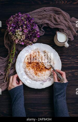 Donna di mangiare budino di riso spolverati con zucchero e cannella Foto Stock
