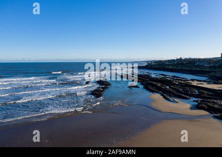 La bassa marea sulla spiaggia di West Sands rivela rocce frastagliate che circondano la città balneare di St Andrews, Scozia. Foto Stock