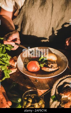 Eldery donna in lino grembiule mangiare turco tradizionale zuppa di carne Haslama con verdure in cucina moderna con interni. Caduta comfort food, Middl regionale Foto Stock