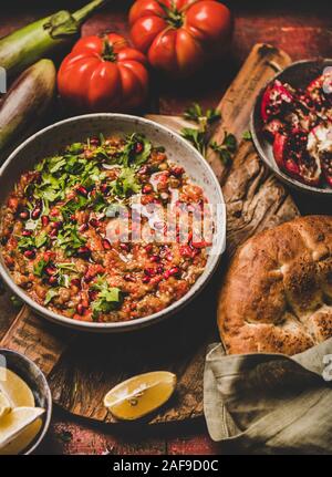 Bagno turco, Medio Oriente meze tradizionale motorino di avviamento. Babaganoush immersione a freddo in una terrina condite con prezzemolo e i semi di melograno, limone con flatbread oltre rustico Foto Stock