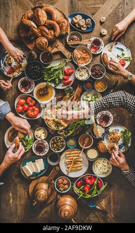 Prima colazione Turca. Flat-lay dei popoli tenendo le mani e mangiare turco la pasticceria, verdura, verdure, formaggi, uova fritte, marmellate e tè in pentola di rame a Foto Stock