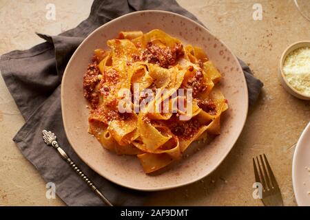 Flatlay con la classica pasta cotta bolognese con papardelle e partite di formaggio parmigiano Foto Stock