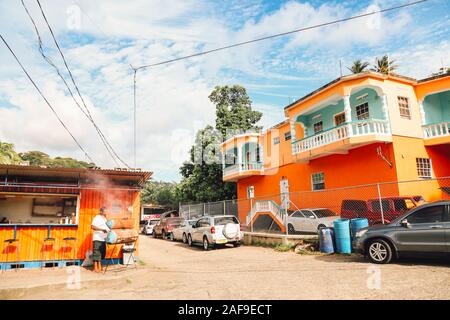 St George, Grenada - 20 Aprile 2018 - L'uomo che fa il barbecue su strada di case colorate di St George, capitale dell'isola dei Caraibi paese Foto Stock