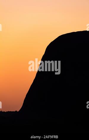 Silhouette fino in prossimità del lato di Uluru al tramonto. Uluru, Territorio del Nord, l'Australia Foto Stock