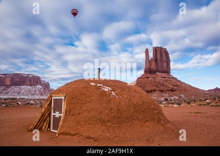 Una mongolfiera volare sopra un tradizionale Navajo hogan e il West mitten in Monument Valley Balloon Festival nella Monument Valley Navajo Tri Foto Stock